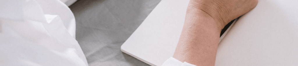 Femme aux cheveux blancs écrivant devant un ordinateur